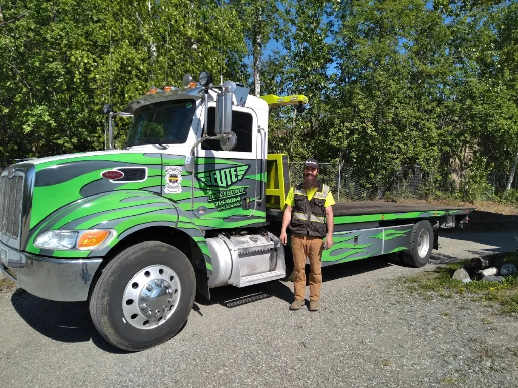 Real Elite Towing custom green Peterbilt flatbed with driver